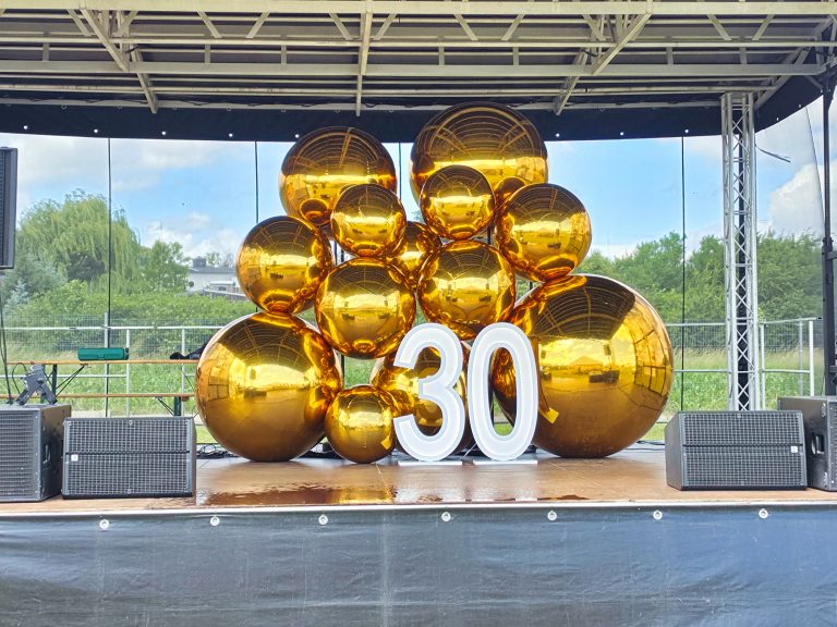 Złote balony kule lustrzane jako dekoracja na imprezie plenerowej.