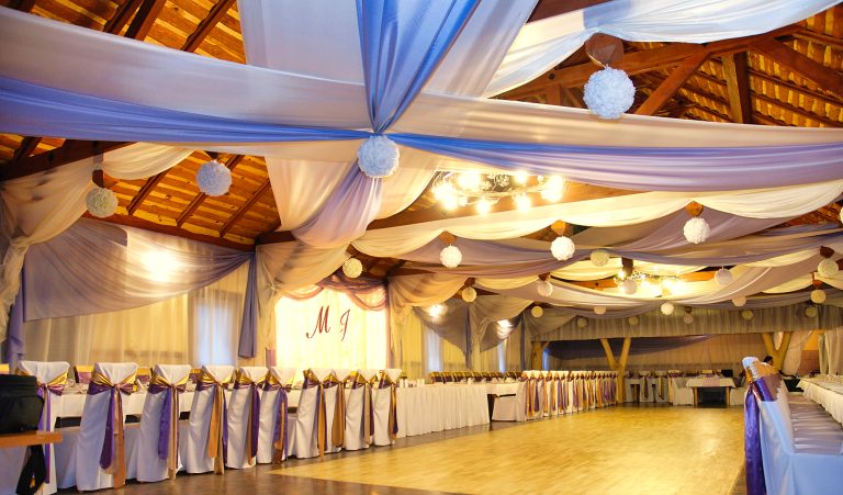 Drewniana sala karczmy przerobiona tkaninami na weselną salę balową