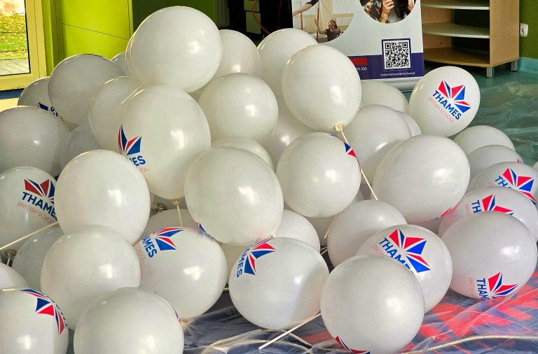 Białe balony z dwukolorowym nadrukiem założone na patyczki.