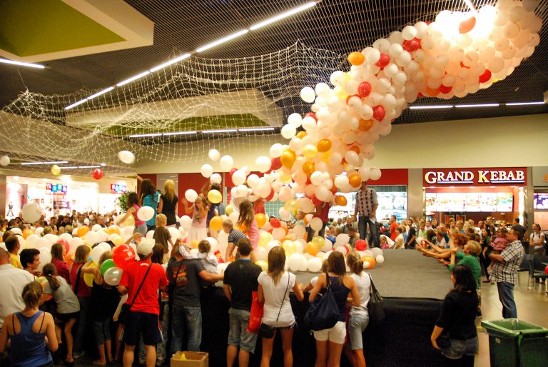 Zrzucanie balonów na ludzi w czasie otwarcia galerii