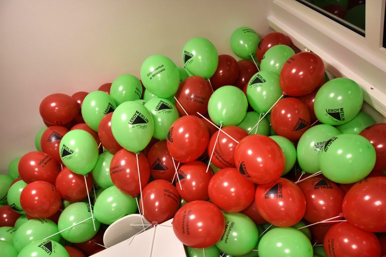 Balony z logo sklepu Leroy Merlin nadmuchane powietrzem i założone na patyczki