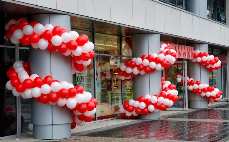 Girlandy z balonów zaplecione na słupach jako dekoracje na otwarcie Rossmana